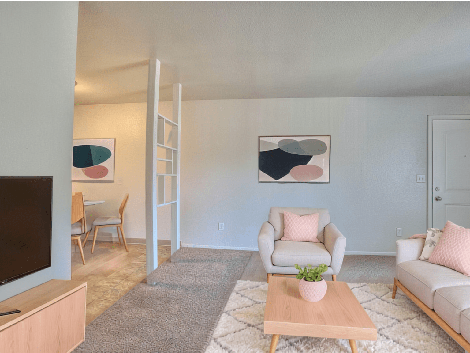 A living room with a white couch, a wooden coffee table, and a painting on the wall.